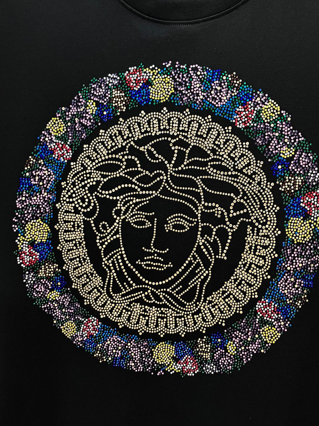 Rhinestone Medusa face graphic centered on a black crewneck T-shirt