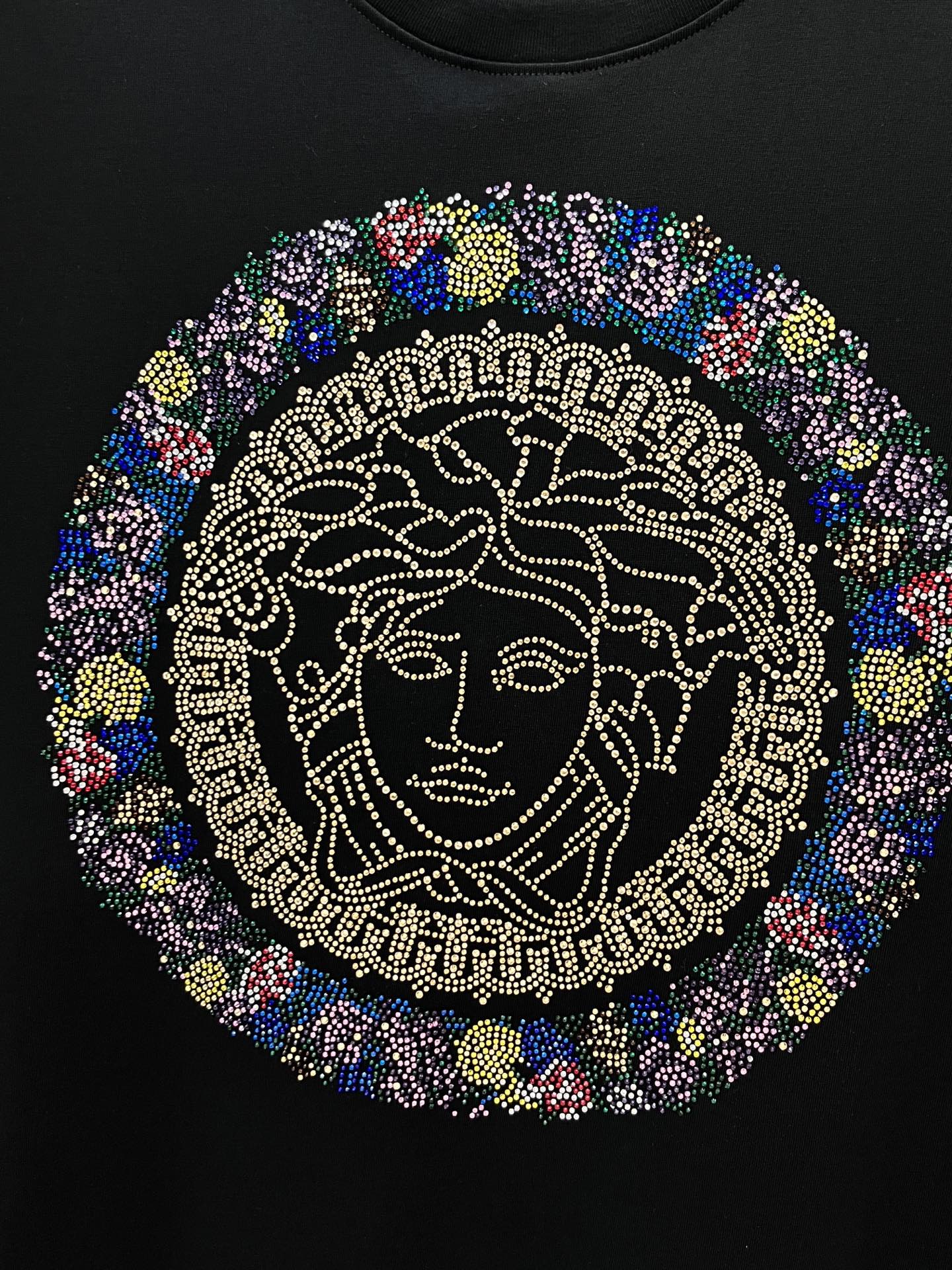 Rhinestone Medusa face graphic centered on a black crewneck T-shirt