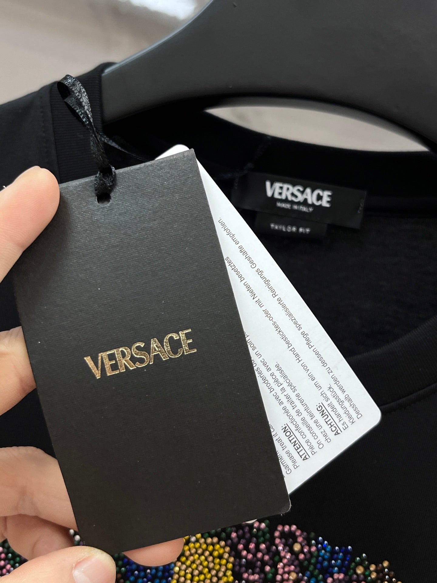 Versace hangtag on black T-shirt collar with white barcode label.