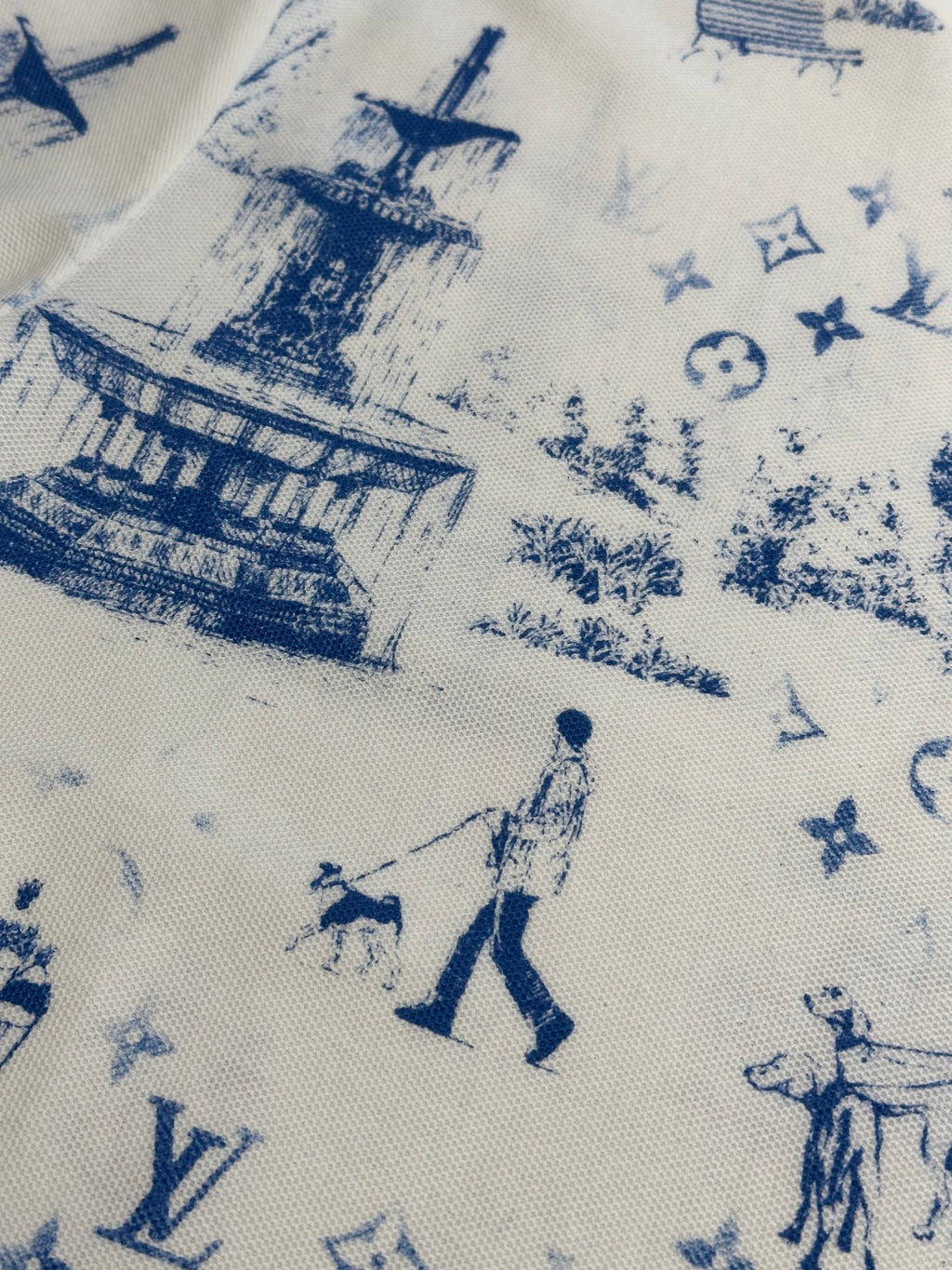 Close-up of off-white fabric with blue toile-style city and figures print