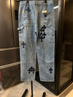 Light-wash denim pants with multiple black cross patches and large side pockets