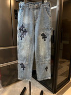 Light-wash denim pants with black cross applique on front leg pockets