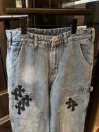Light-wash denim pants with black cross patches on side seams and front pockets