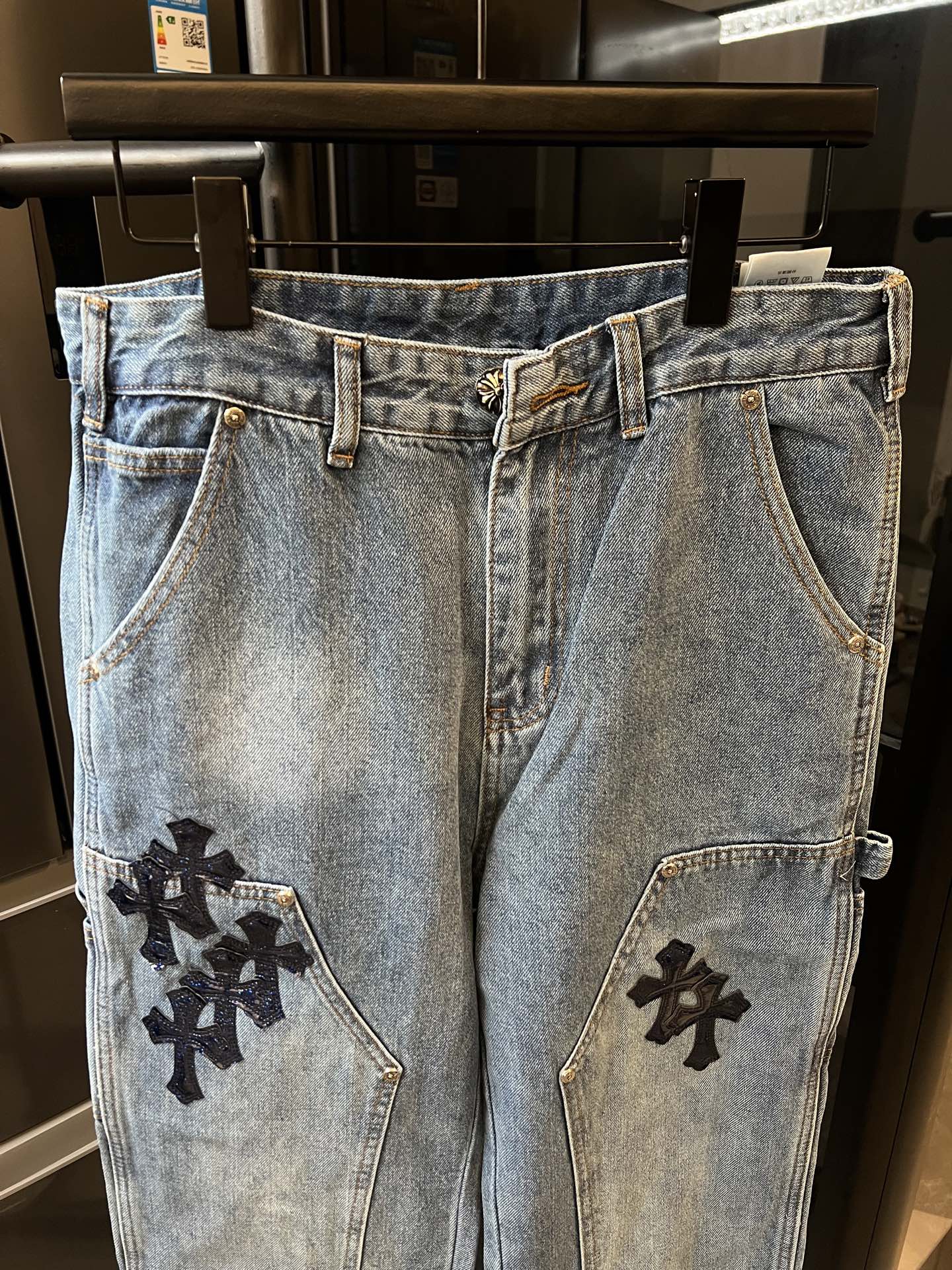 Light-wash denim pants with black cross patches on side seams and front pockets