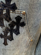 Denim pocket with embroidered black cross pattern and gold-tone button