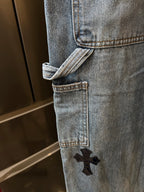 Light-wash denim pant hem with cuff and embroidered black cross patch