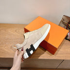 Cream suede sneaker with black-and-white outsole, side view held by hand