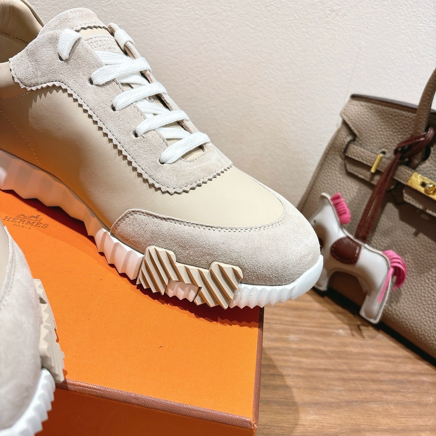 Cream unisex sneaker with white laces, stitched trim, and textured ridged outsole.
