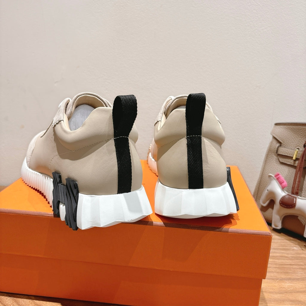 Cream unisex sneakers showing rear with black heel tabs and cushioned sole.