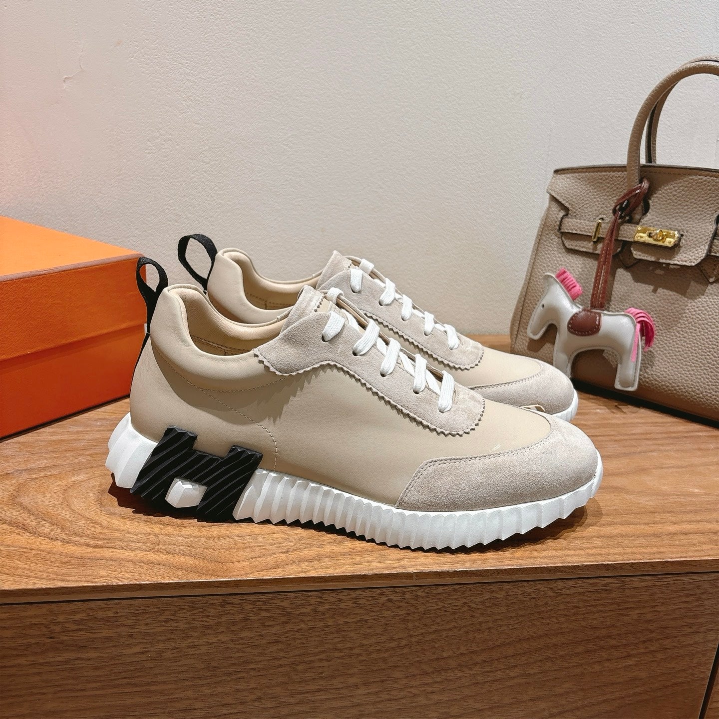 Cream unisex sneakers with white laces, textured side panel, and chunky sole.