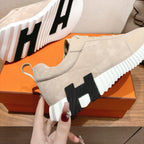 Cream suede sneaker with black logo patch on ribbed platform sole, close-up