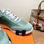 Hermes mint unisex sneaker close-up: white laces, scalloped edge trim, black tread sole.
