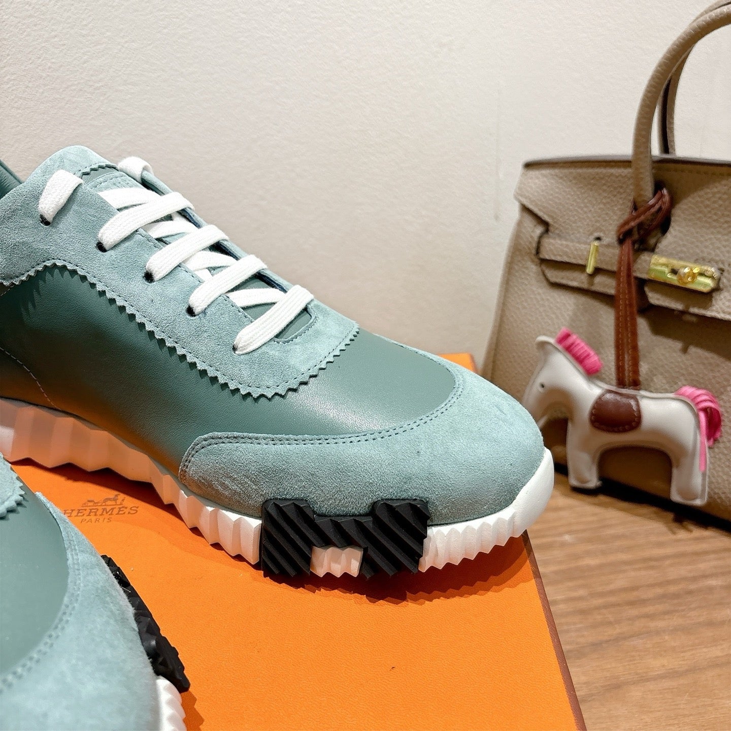 Hermes mint unisex sneaker close-up: white laces, scalloped edge trim, black tread sole.