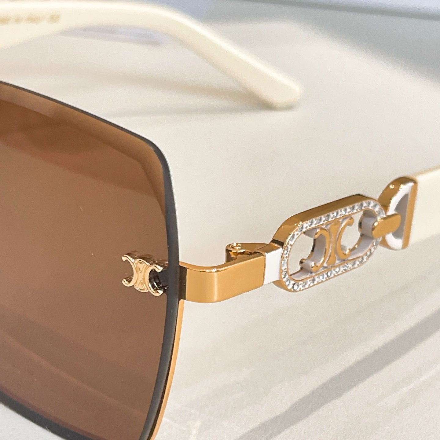 Celine sunglasses close-up: gold temple with crystal-studded logo detail