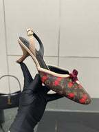 Women's Louis Vuitton slingback heel held by glove, monogram with red bow at front