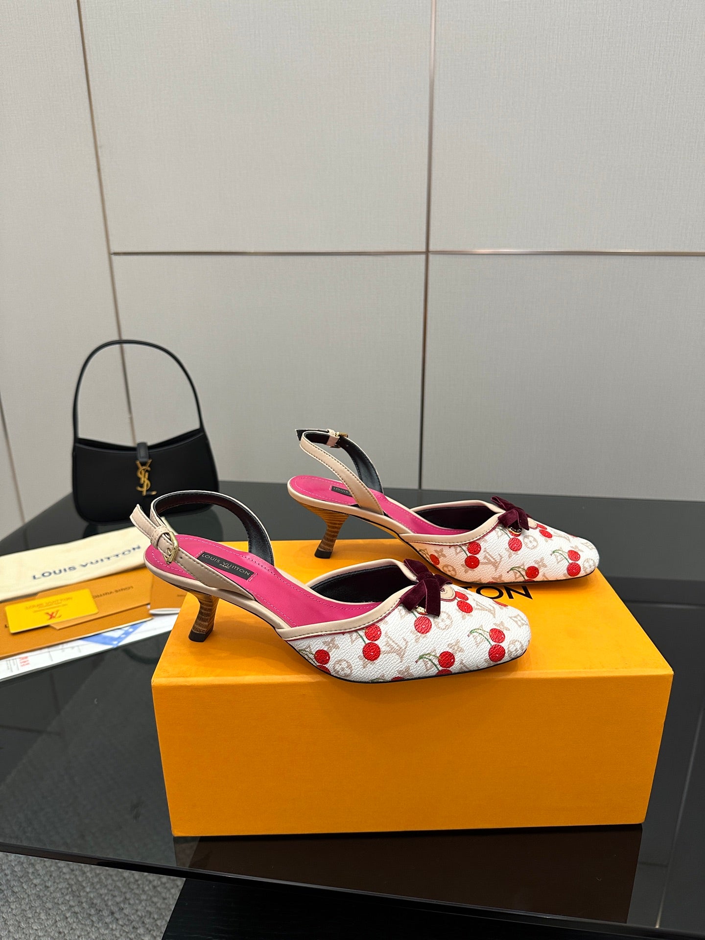Heeled slingback shoes in white with red cherries, fuchsia insoles, and bow detail.