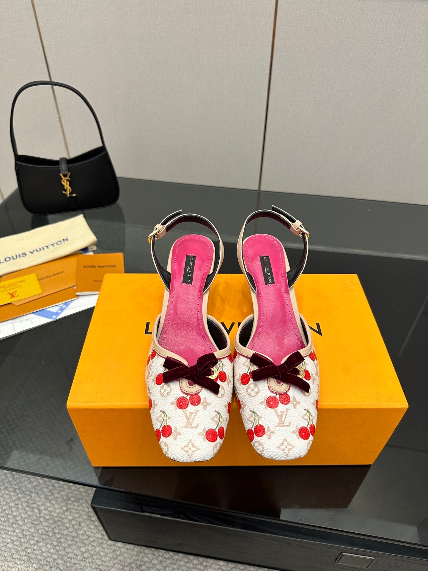 Heeled slingback shoes with red cherry print, fuchsia lining, and bow detail on box.