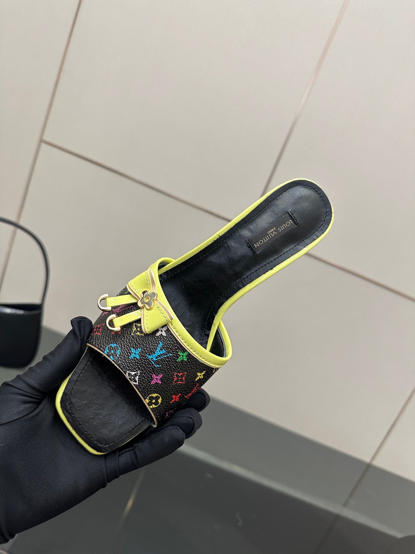 Louis Vuitton slide sandal in multicolor monogram with neon green trim, held in glove