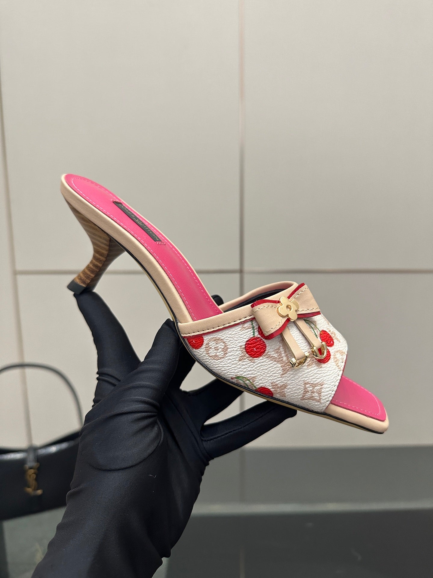 Pink and white cherry print heeled mule held in black glove
