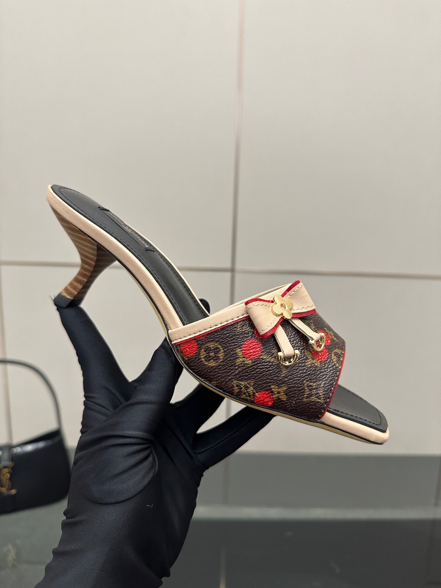 Louis Vuitton slide mule held in hand, multicolor monogram fabric with bow strap