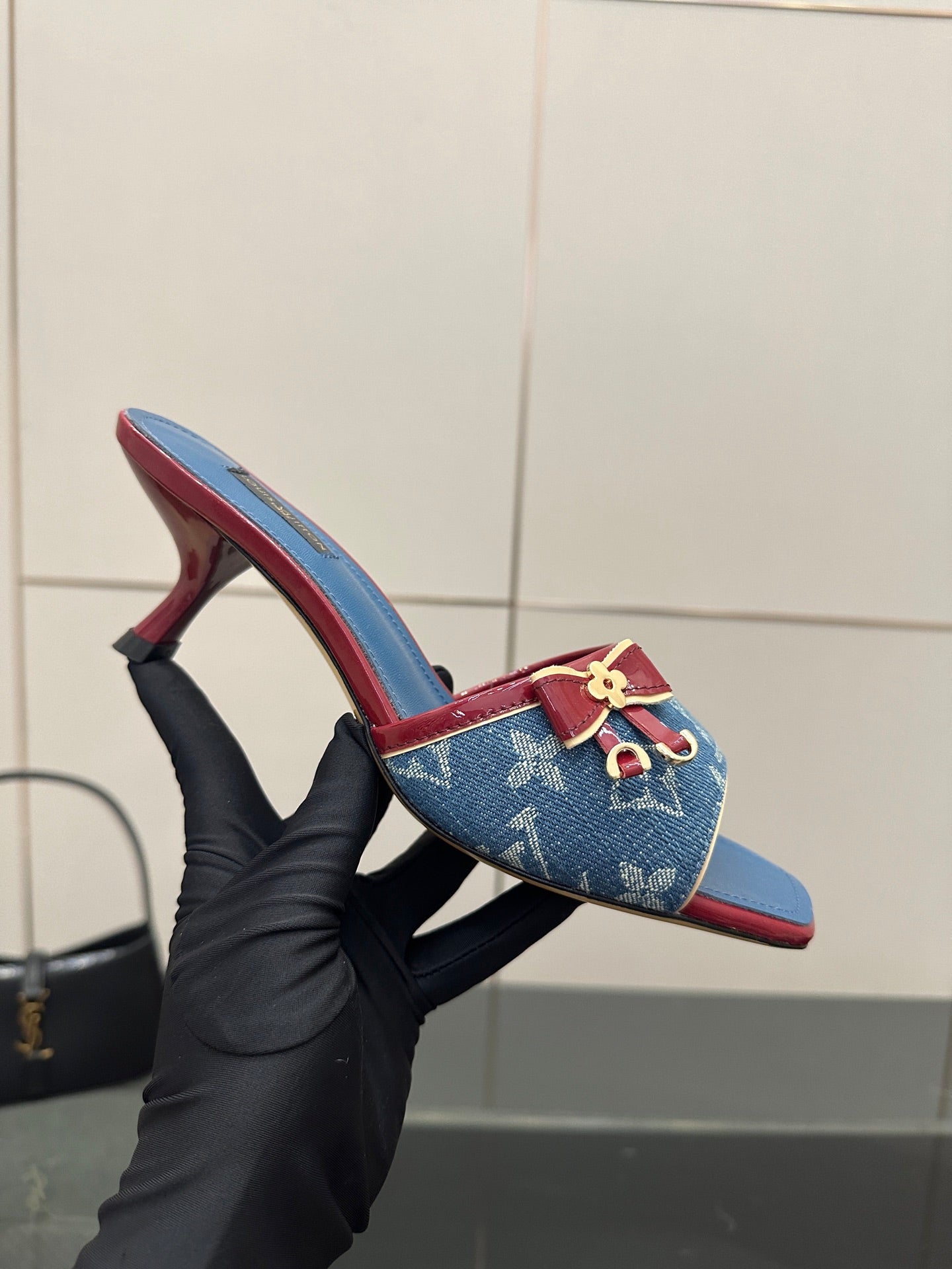 Louis Vuitton women's blue monogram heeled mule held in hand with red-lined edge