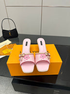 Pink leather slide sandals with floral appliqué, buckle strap, and low block heel