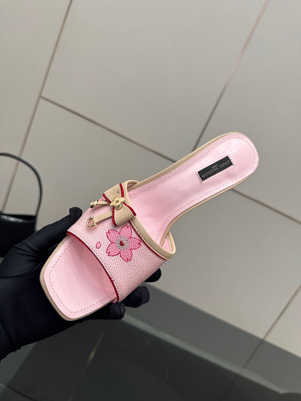 Pink leather slide sandal with floral appliqué strap and top logo label