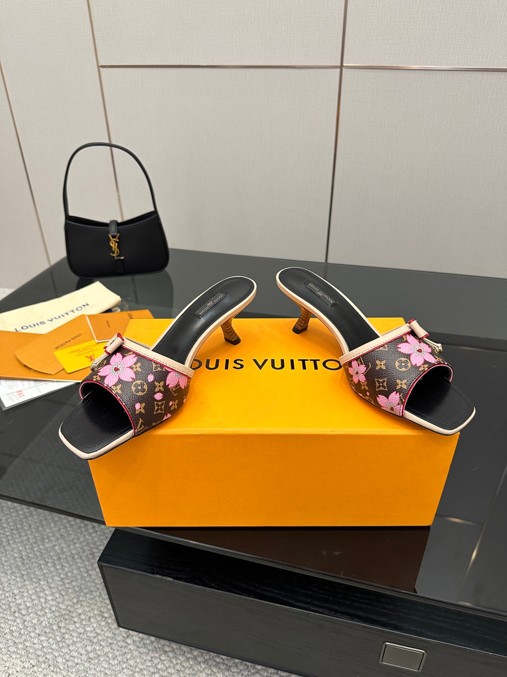 Women's heeled mules with open toe, black floral print, pink bow straps, gold heel