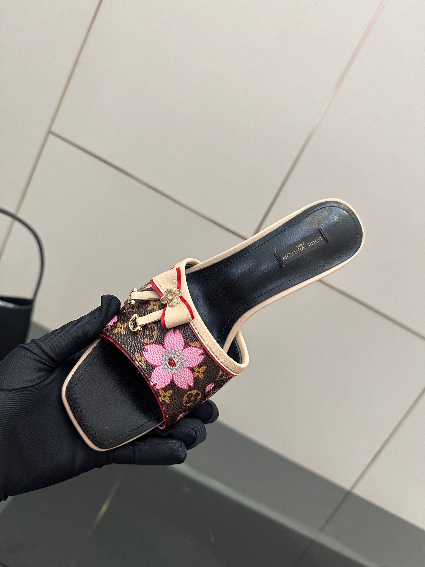 Women's heeled mules, close-up in hand: black base with pink floral bow strap
