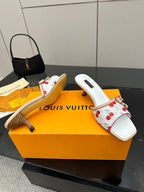 Women’s cherry-print mules with red bows, gold hardware, white straps, and mid heel