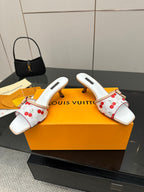 Women’s white mules with red cherry pattern, gold-toned bow ties, and open toe