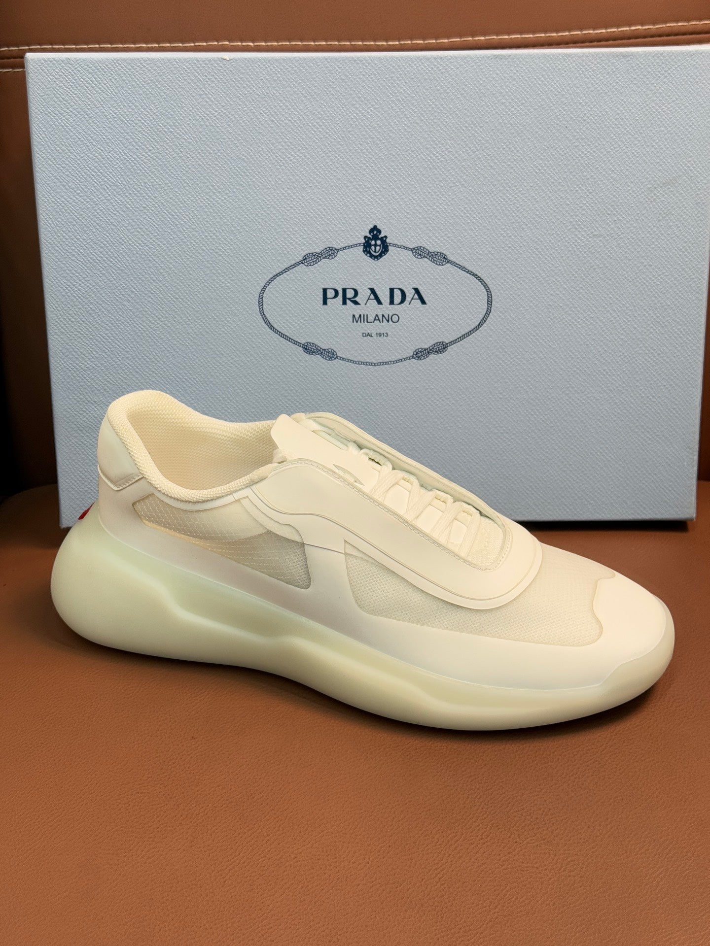 Prada unisex low-top sneaker, light cream leather, side profile with lace-up and swoosh-like patch