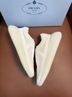 Prada unisex low-top sneakers, light cream leather, angled view showing side paneling