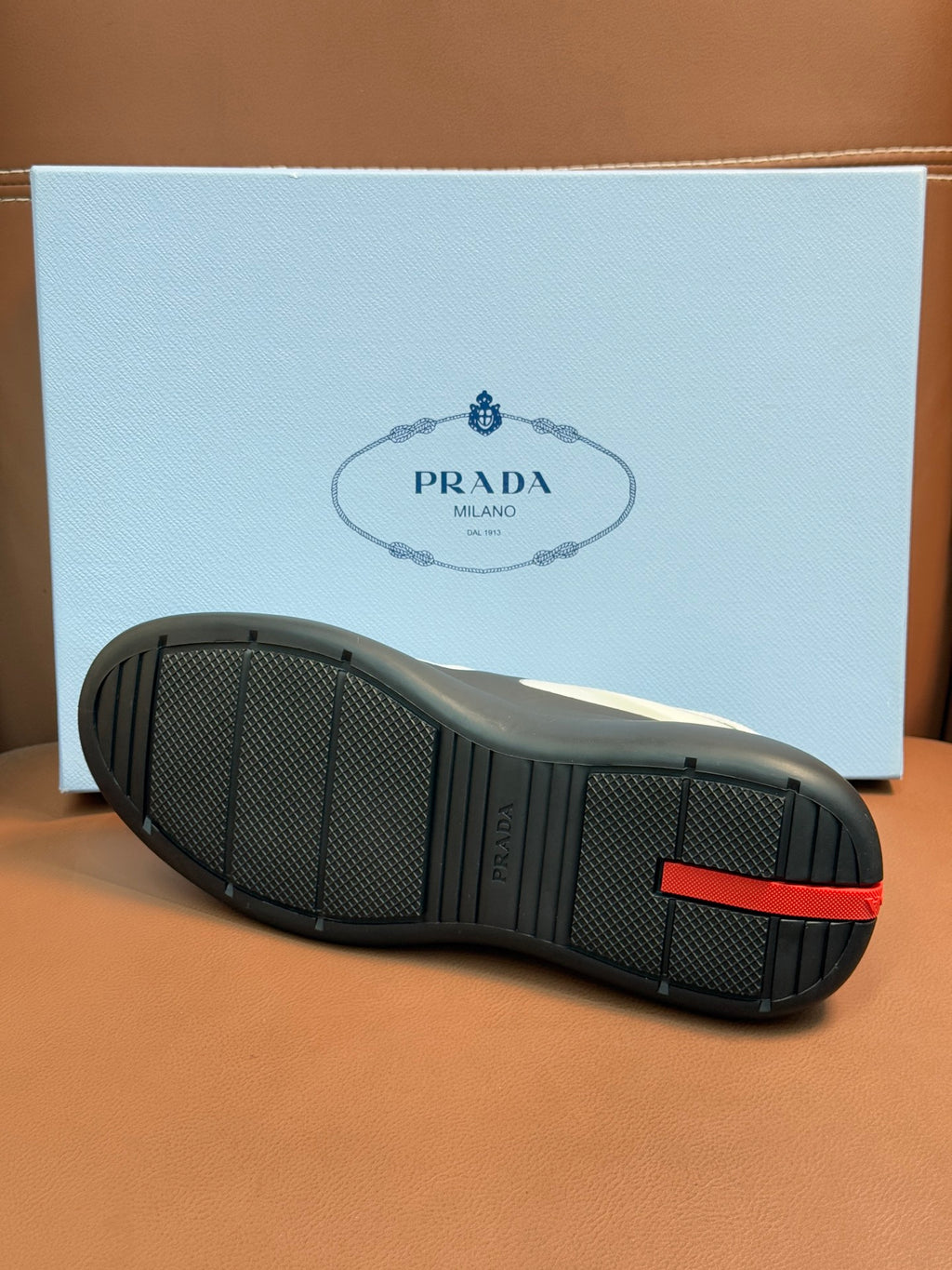 Shoe outsole view with textured black rubber tread and red accent tab