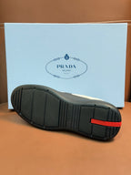 Shoe outsole view with textured black rubber tread and red accent tab