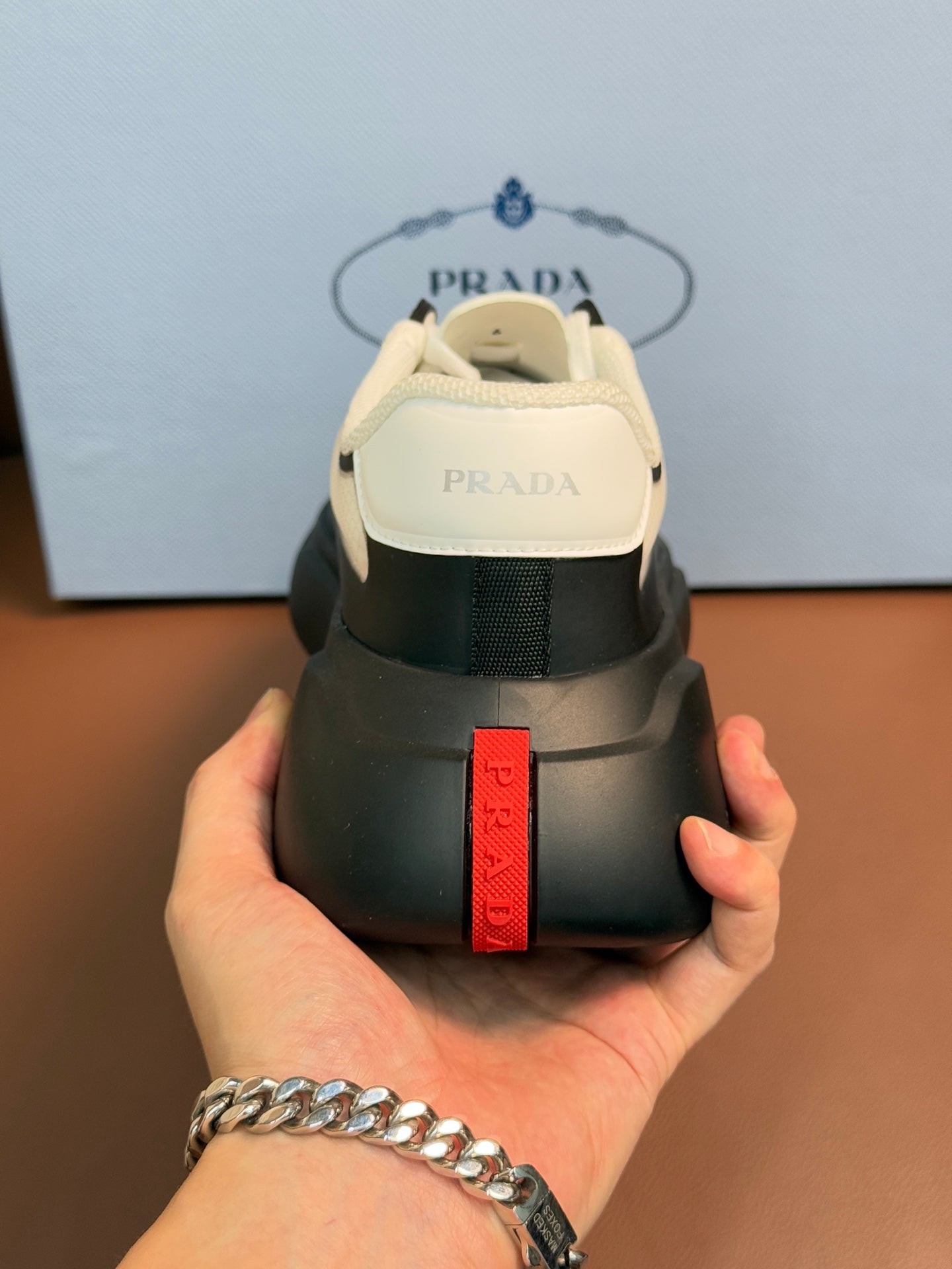 Sneaker heel with PRADA red vertical label and cream heel tab on dark gray