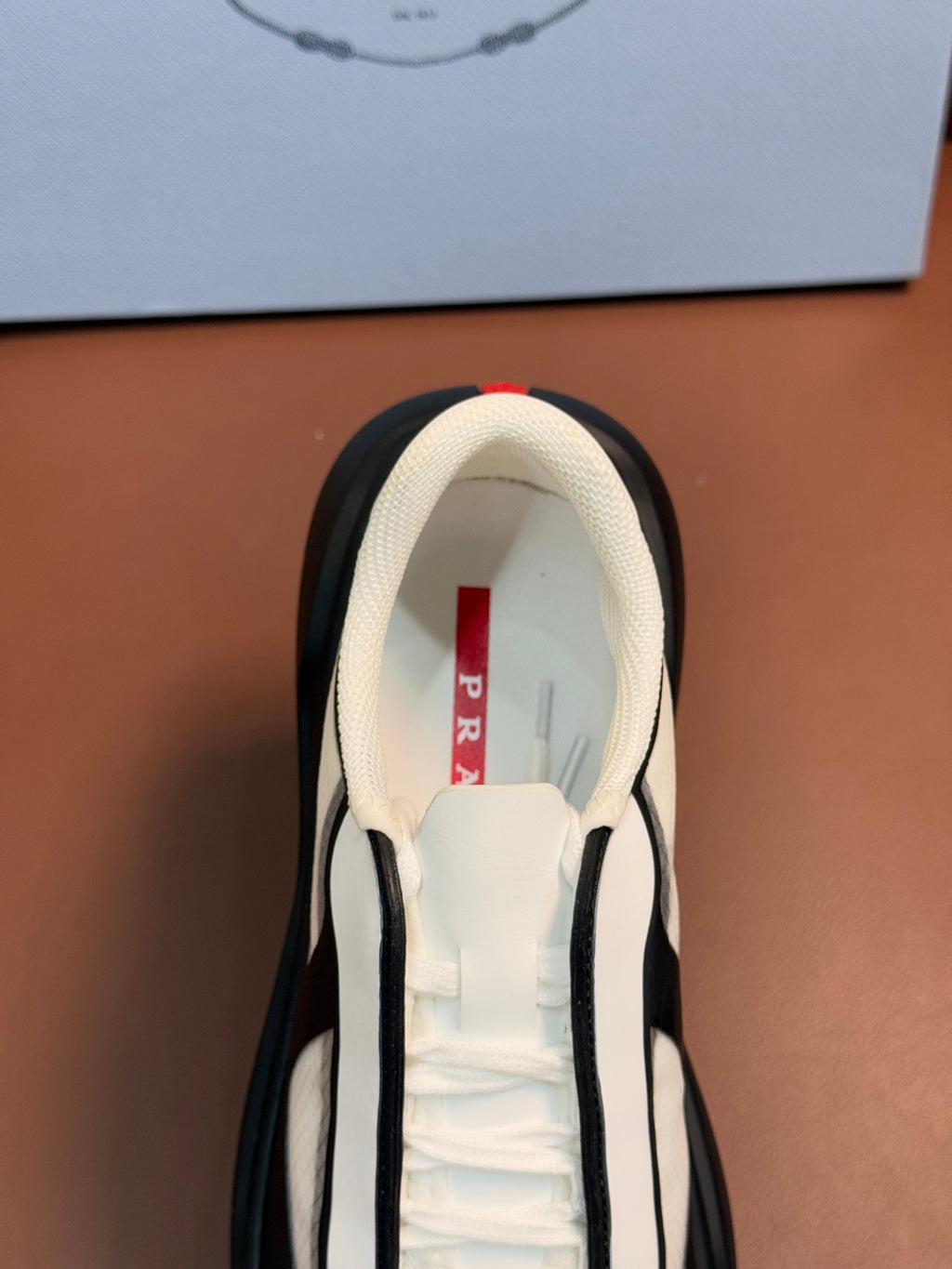 Sneaker interior view with cream lining and PRADA red label on tongue
