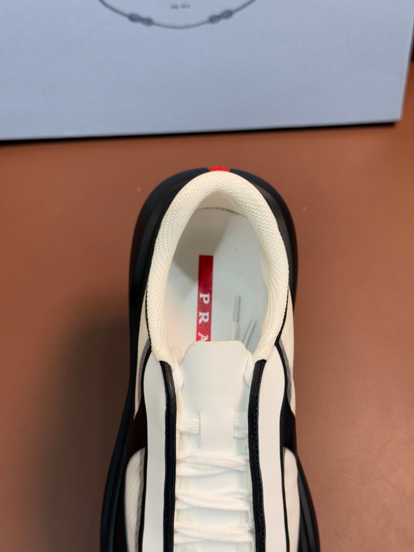 Sneaker interior view with cream lining and PRADA red label on tongue