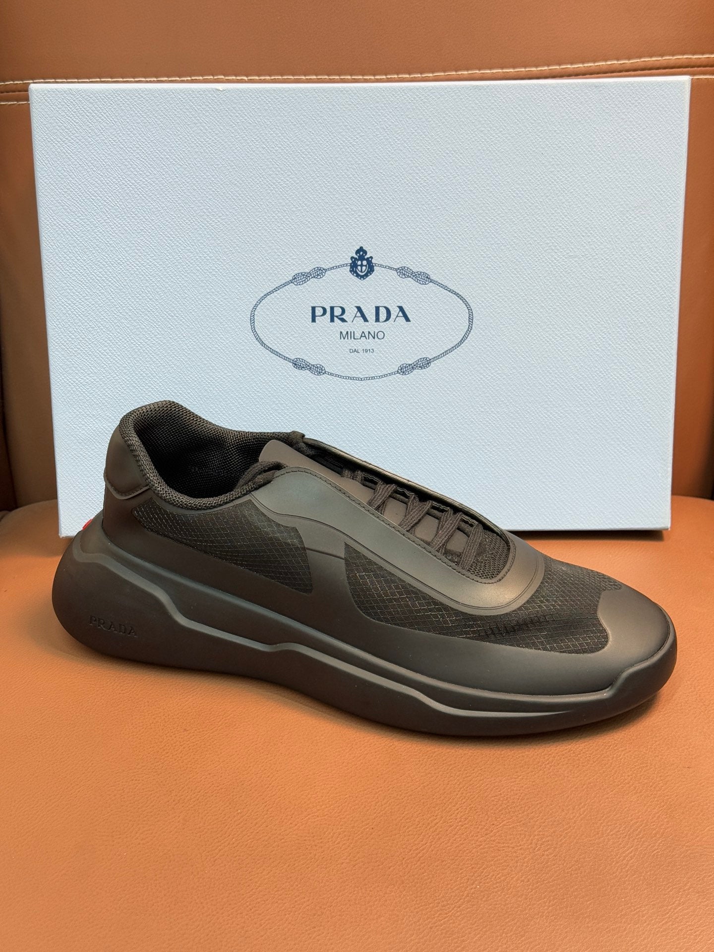 Prada unisex sneakers, dark gray, 3/4 view showing textured mesh upper.