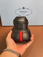 Prada unisex sneaker heel, dark gray with vertical red PRADA strap detail.