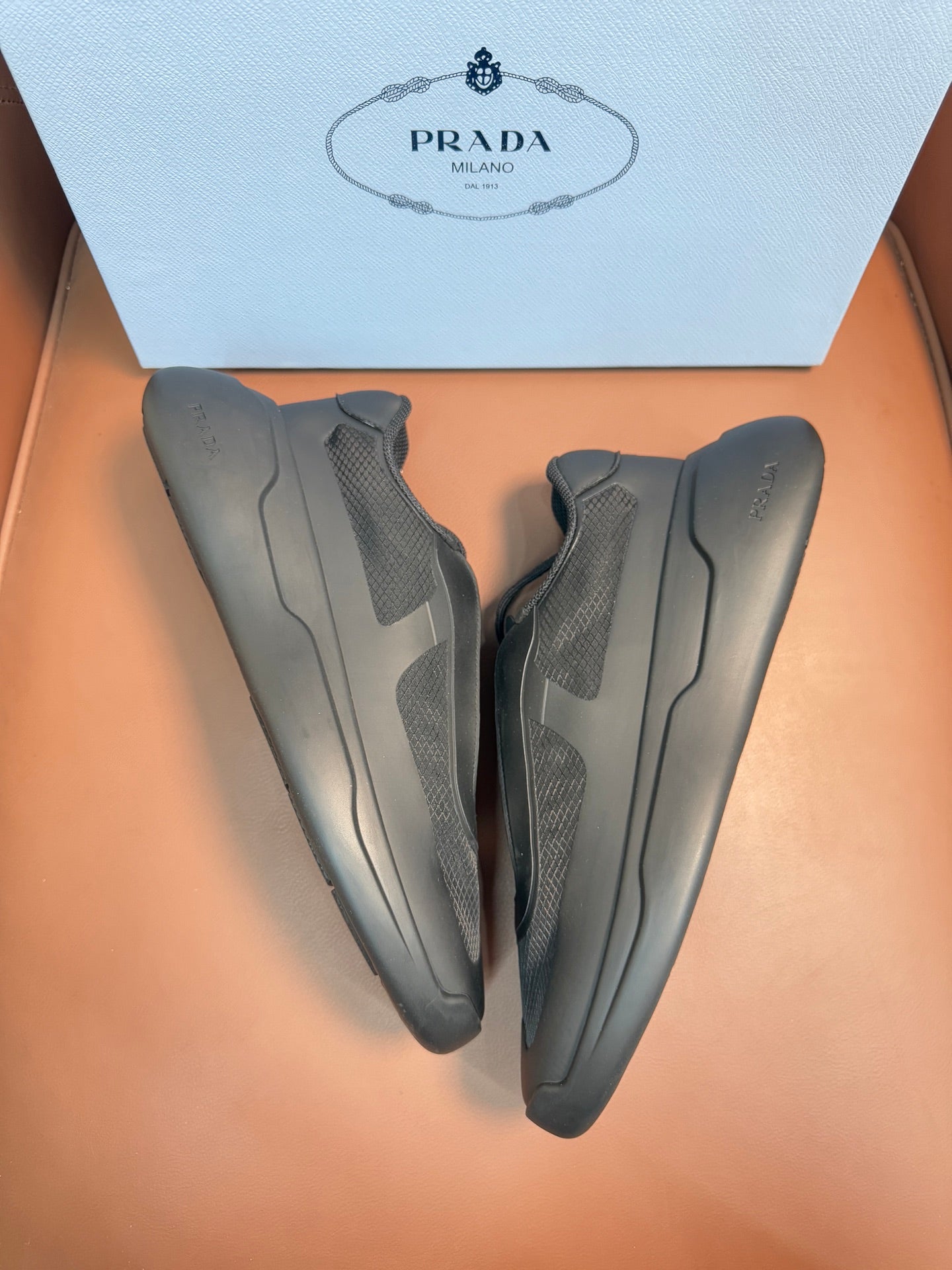 Prada unisex sneakers, dark gray, heel view with molded side stripes.