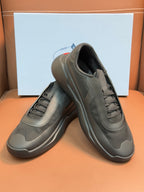 Prada unisex sneakers, dark gray, angled view with lace-up tongue and padded collar.