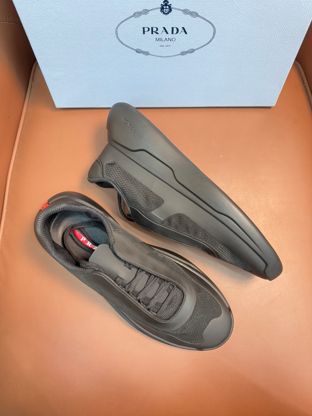 Prada unisex sneakers, dark gray, side profile with lace-up and rubber sole.