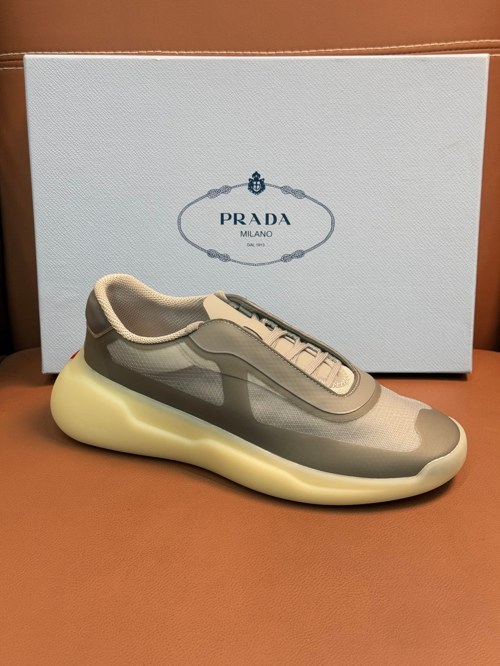 Prada unisex sneakers, front view, cream-beige upper, gray overlays, laces, yellow sole