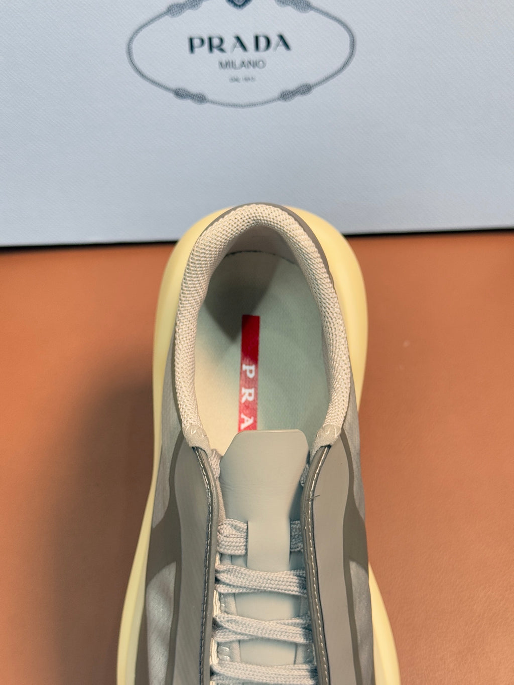 Prada unisex sneakers, inner view of tongue and laces, cream lining, red logo tab