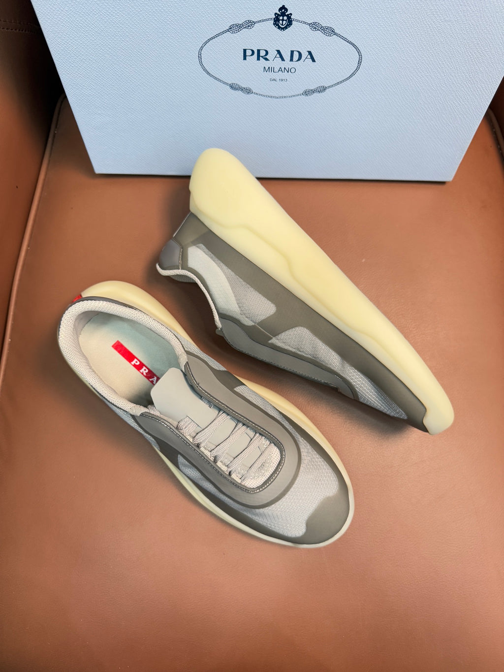 Prada unisex sneakers pair, cream-yellow tone, gray camo panels, laced, chunky sole