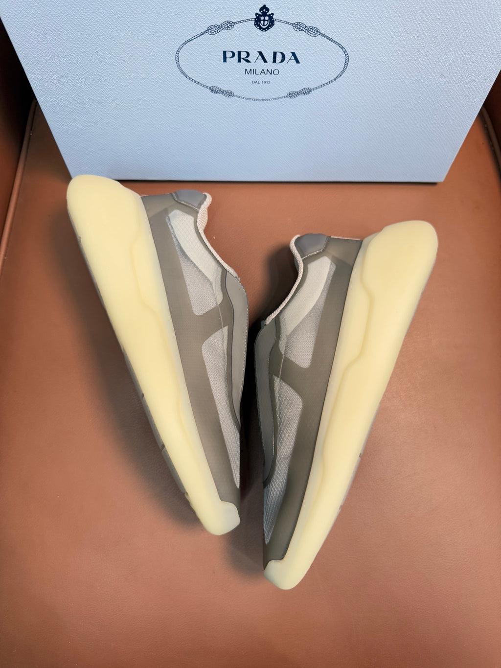 Prada unisex sneakers pair, cream-yellow heels, gray and beige uppers, laced
