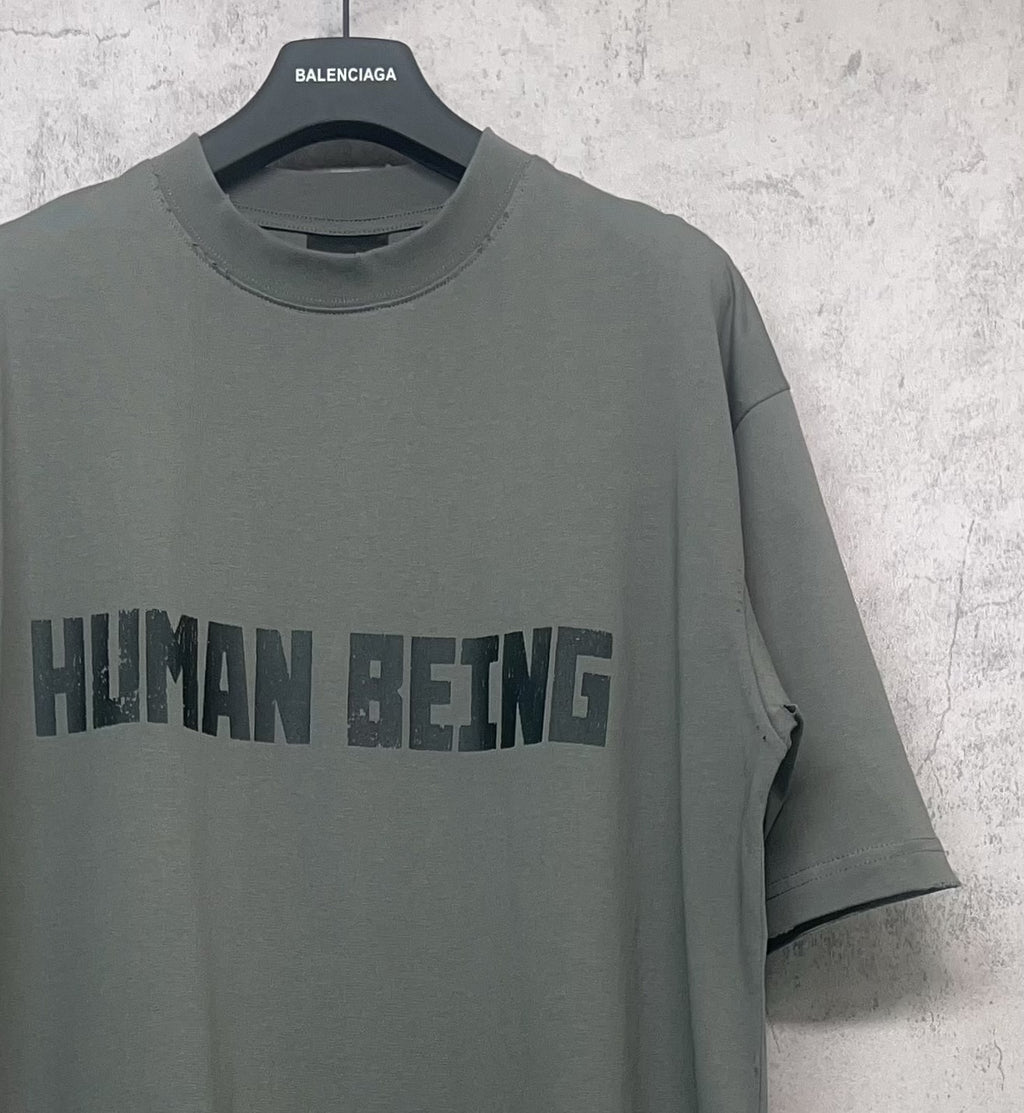Balenciaga crewneck T-shirt side angle, dark gray-green with “HUMAN BEING” print