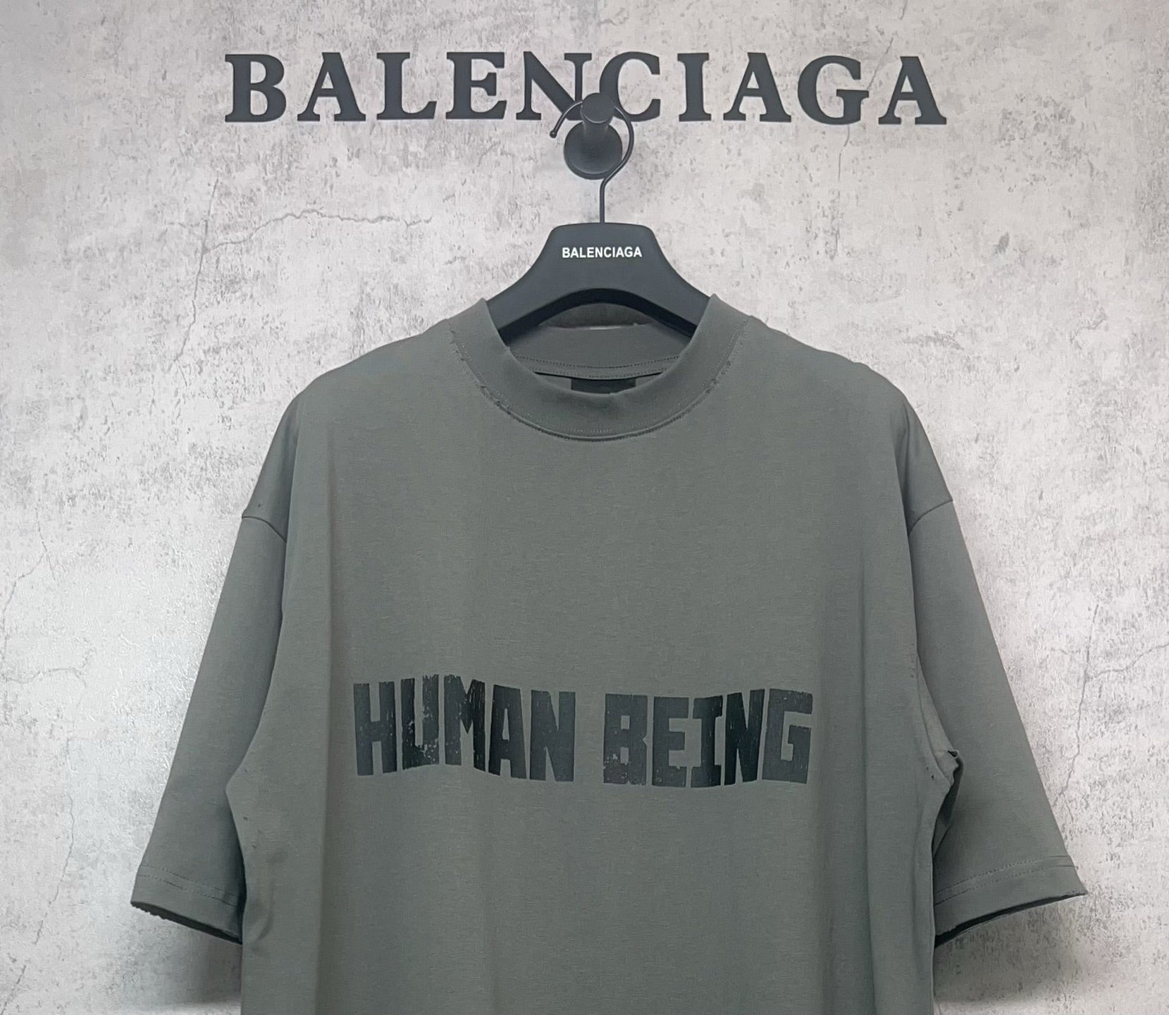 Balenciaga crewneck T-shirt close-up with “HUMAN BEING” graphic, dark gray-green
