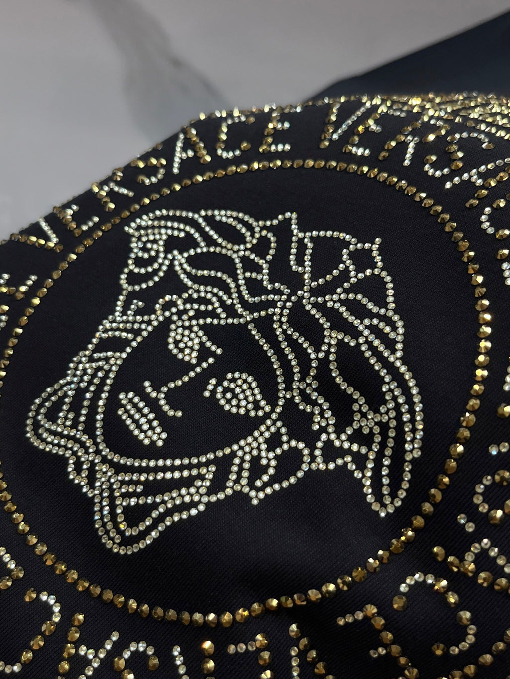 Versace black T-shirt close-up of gold Medusa head emblem